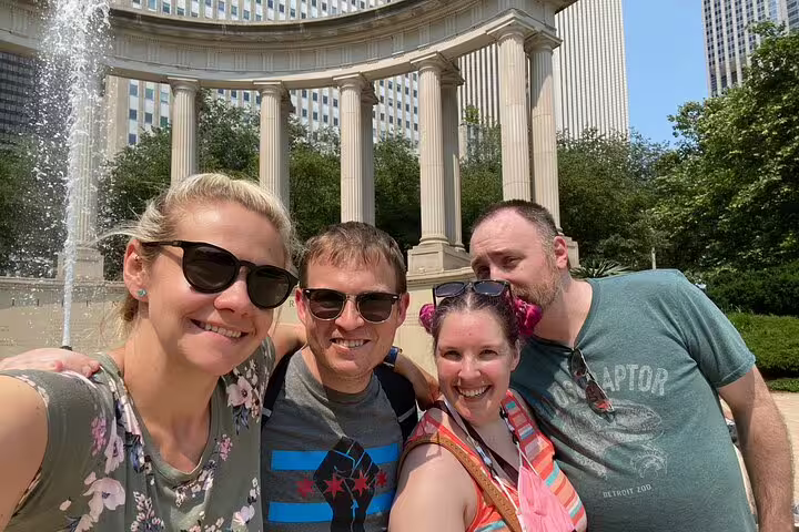 Four friends smiling for selfie at Wrigley Square colonnade fountain in Grant Park Chicago