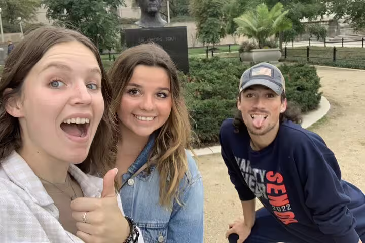 Three friends making fun poses near a bust sculpture in Grant Park Chicago