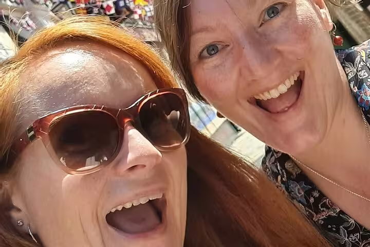 Two smiling women taking a selfie outdoors on a sunny day during a walking tour in Greenwich