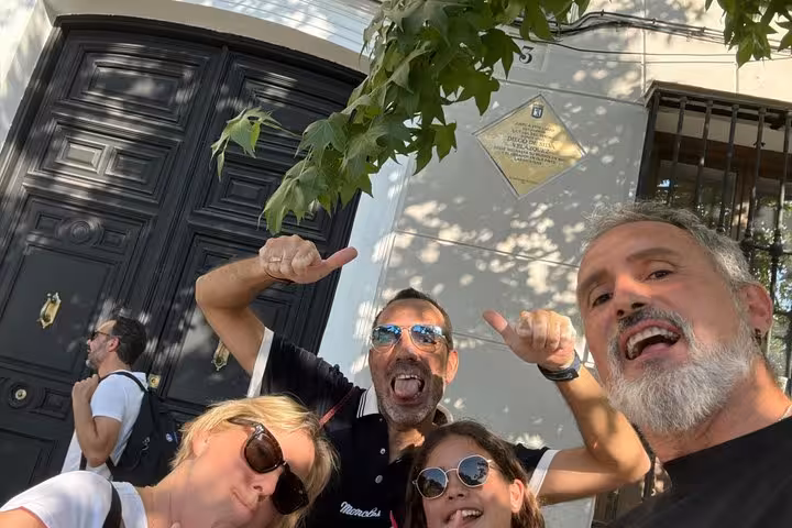 Group of friends taking a selfie in front of a historic Madrid building with commemorative plaque