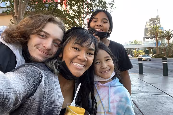 Group of four smiling friends taking a selfie on the Las Vegas Strip near New York-New York Hotel