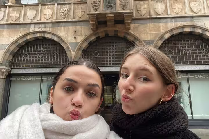 Two women making duck faces selfie in front of Banco BPM building in Milan city center