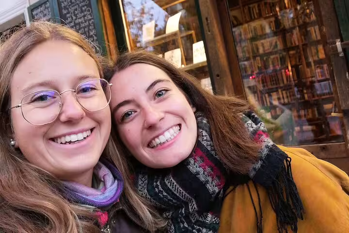 Two smiling women taking a selfie outside a bookshop in Paris on a Seine walking tour