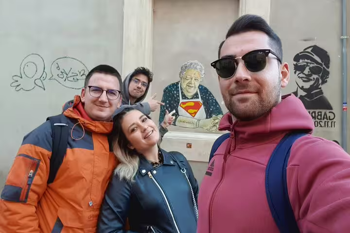 Four friends taking a selfie in front of street art murals in Trastevere, Rome
