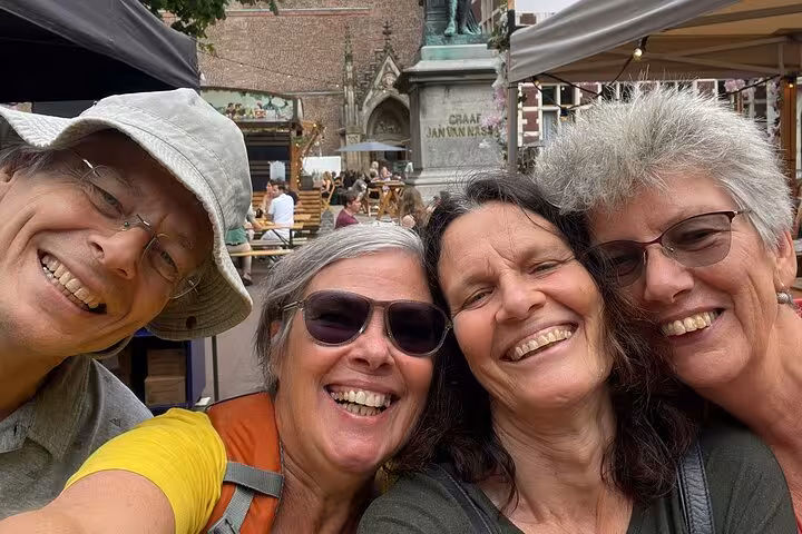 Four women smiling together at an outdoor market near Graaf Jan van Nassau statue in Utrecht