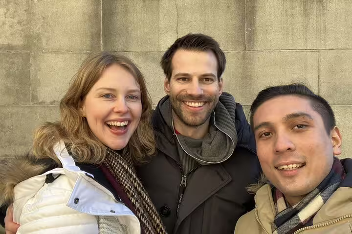 Three smiling visitors posing together outdoors in Zurich during a walking tour