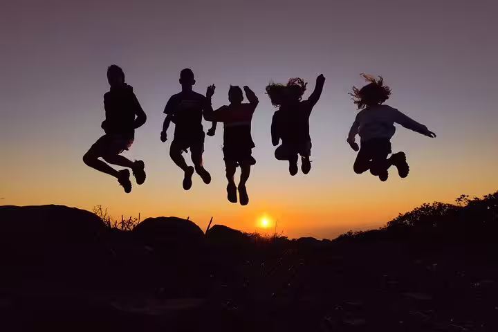 Friends jumping joyfully at sunset in Algarve Natural Park's secret spot on West Coast off-road tour.