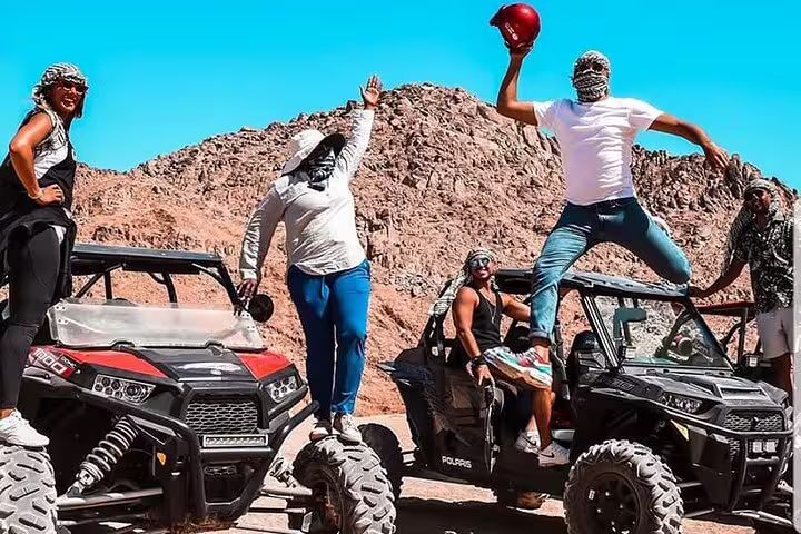 Friends posing on twin off-road buggies during Sharm El Sheikh double buggy desert safari in Sinai mountains