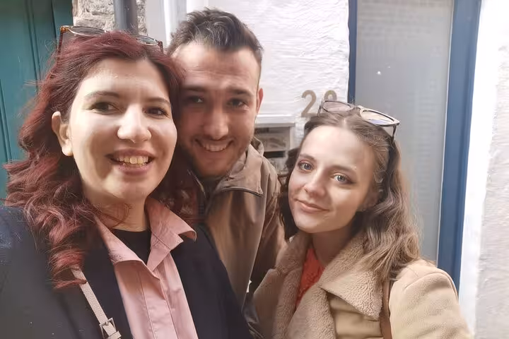 Three smiling tourists posing together on a charming street in Bruges during a walking tour