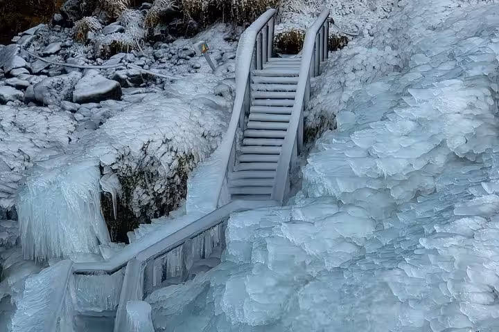 Ice-covered wooden staircase surrounded by frozen rocks and icicles on Iceland's south coast in winter