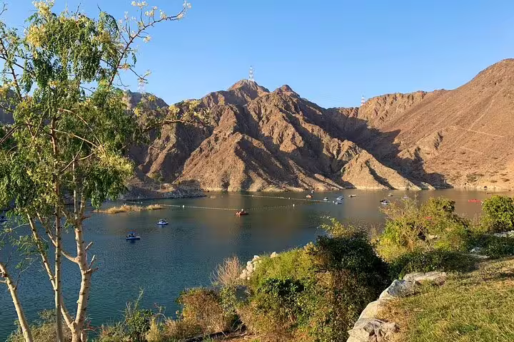 Serene lake surrounded by rugged mountains and greenery in Fujairah, perfect for nature exploration and relaxation.