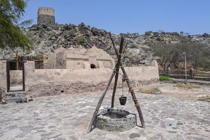 Ancient watchtower and mosque surrounded by rocky landscape in Fujairah, highlighting historical exploration opportunities.