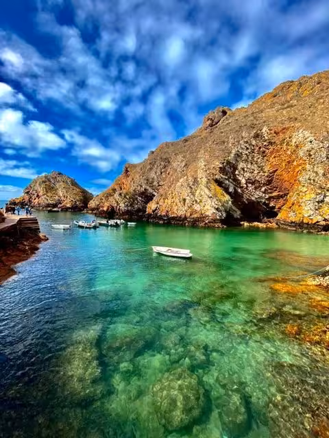 Crystal-clear turquoise cove with small boats and rocky cliffs, ideal for a full day pack coastal tour