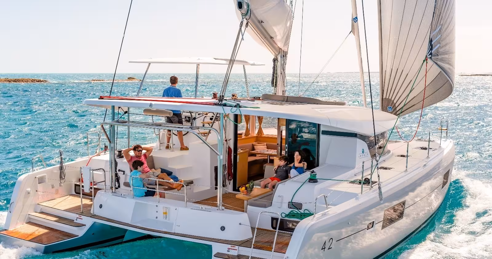 Guests relaxing on luxury VIP catamaran deck during Fun & Swim cruise, sailing over clear blue water