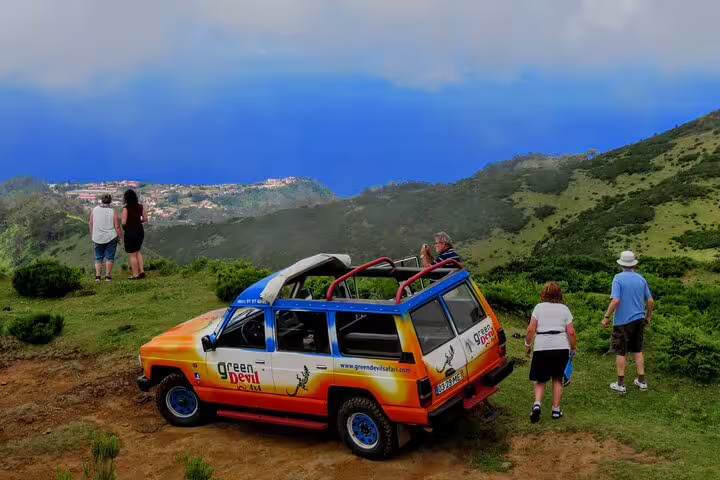 Tourists enjoy a scenic viewpoint with a colorful 4WD vehicle during the Local Farmers Market and 4WD Experience from Funchal.