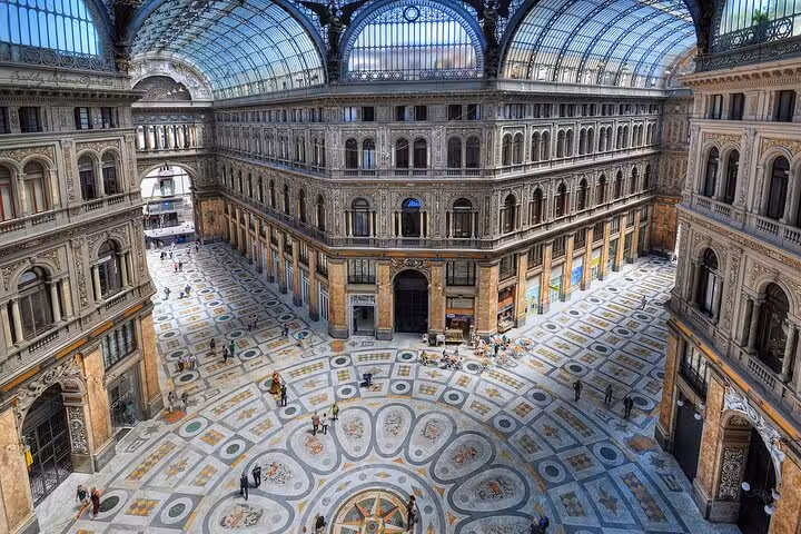 The stunning interior of Galleria Umberto I in Naples, featuring ornate architecture and a grand glass dome.