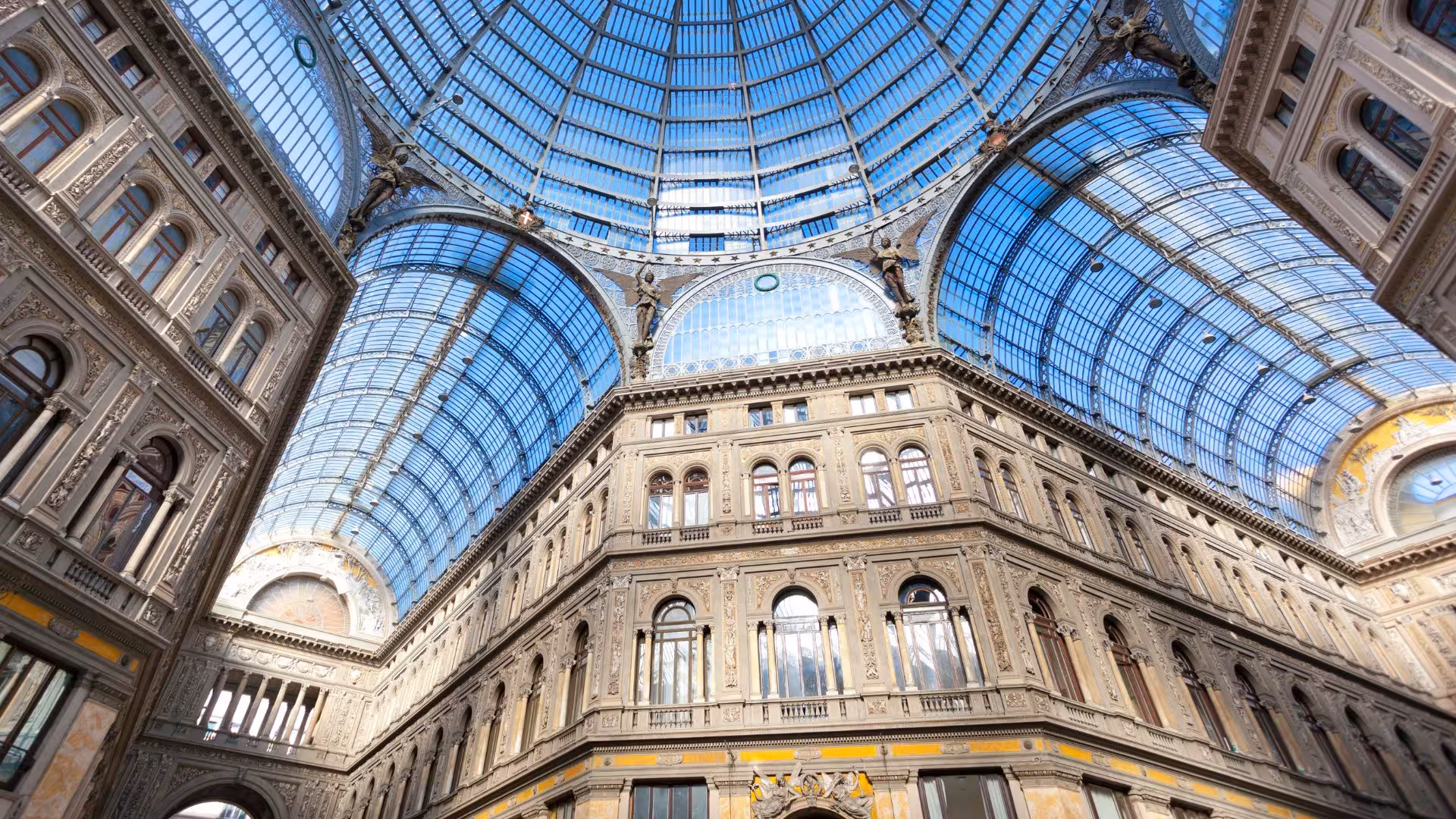 Stunning glass dome and ornate architecture of Galleria Umberto I in Naples, Italy, under bright daylight.