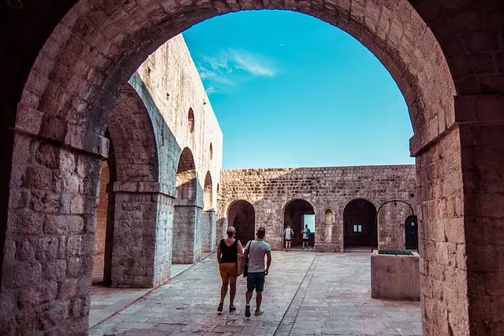 Visitors walk through stone arches at Dubrovnik fortress, a Game of Thrones walking tour filming location