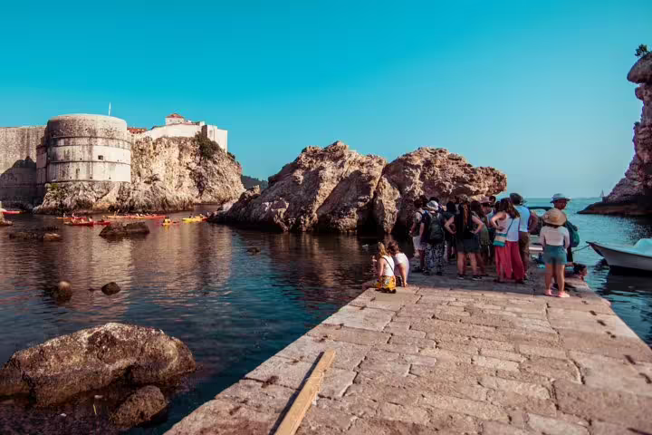 Tour group by Dubrovnik Old Town harbor rocks, Game of Thrones walking tour filming location viewpoint