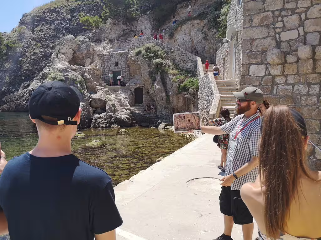 Guide shows Game of Thrones filming photo at Dubrovnik West Harbor, part of 3 hour Lokrum tour experience
