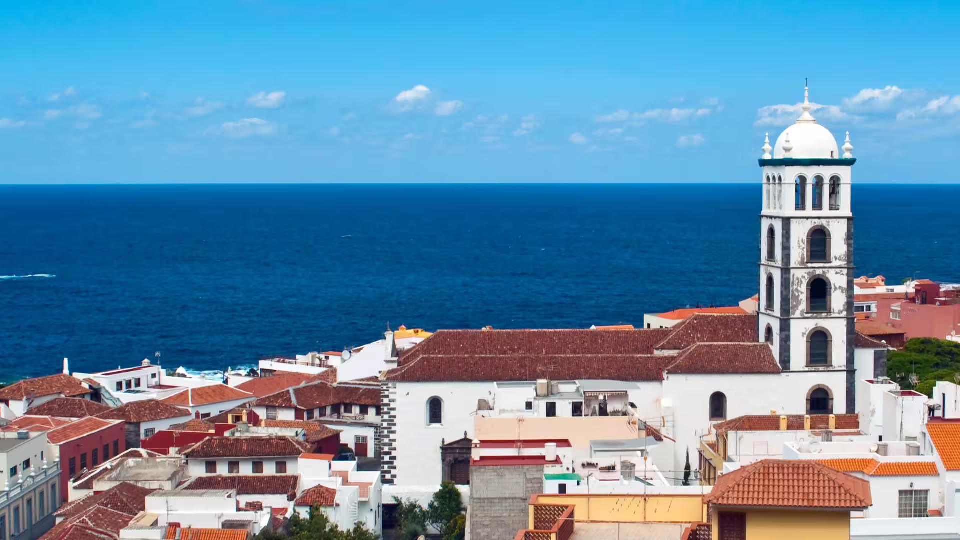 Scenic view of Garachico's historic architecture with a church tower overlooking the vast Atlantic Ocean.