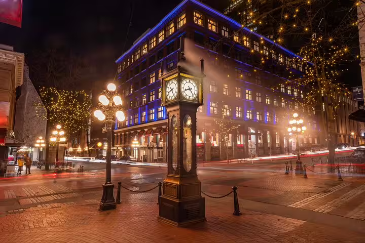 Gastown Steam Clock lit up at night with festive lights and historic buildings in Vancouver