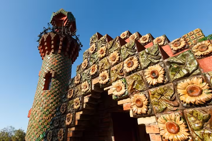 Vibrant ceramic sunflower tiles and ornate tower of El Capricho, a Gaudi masterpiece in Comillas, on a sunny day.