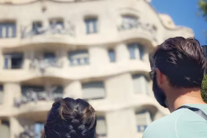 Visitors gaze at the unique wavy facade of Gaudi's Casa Milà, an iconic example of modernist architecture in Barcelona.