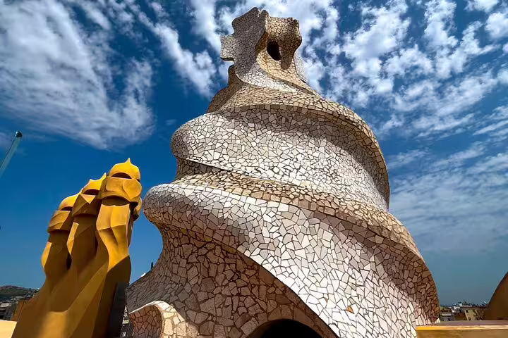 Close-up of Gaudí’s sculpted chimneys and spiral tower on La Pedrera rooftop in Barcelona under a bright blue Mediterranean sky