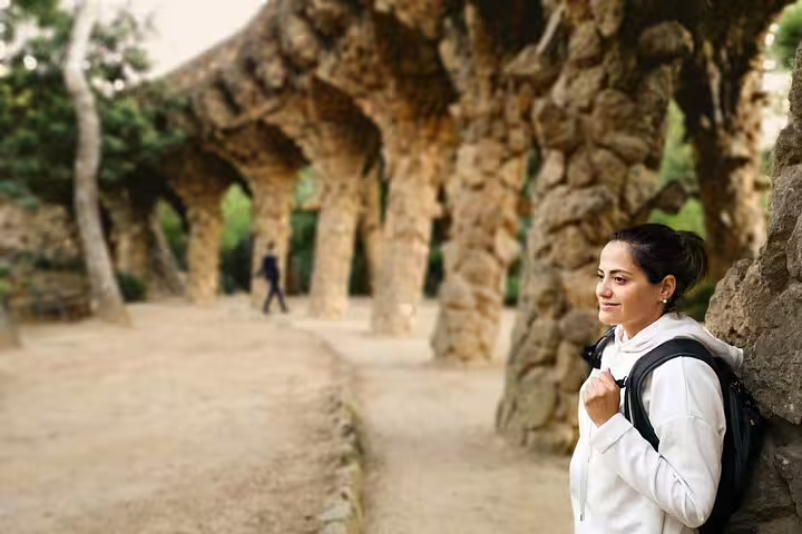 A traveler enjoys the unique stone architecture of Park Güell during a 2-day Gaudi tour including Sagrada Familia and Montserrat.