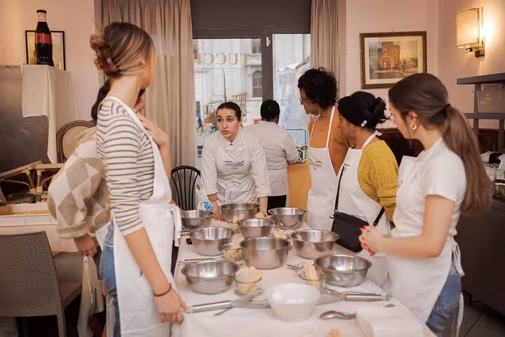 Participants in a gelato and fettuccine cooking class in Rome gather around a table with mixing bowls.