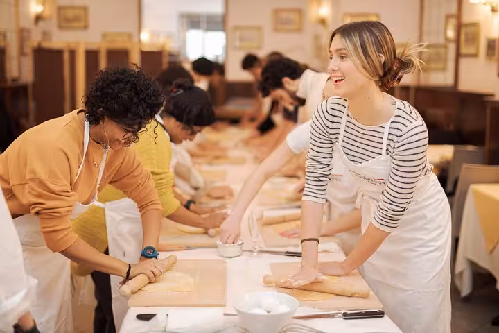 Group of people rolling pasta dough during a lively cooking class in Rome's Piazza Navona.
