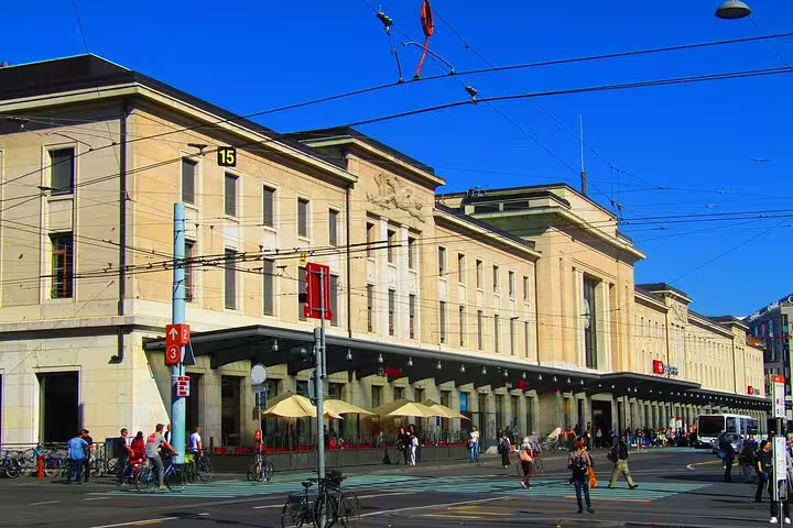 Geneva Cornavin train station facade with pedestrians and tram wires on a sunny day