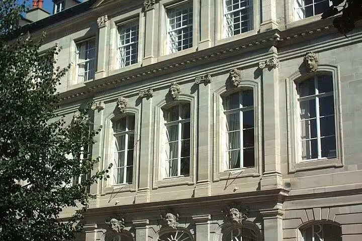 Historic stone building facade with ornate sculptural details and arched windows in Geneva Switzerland