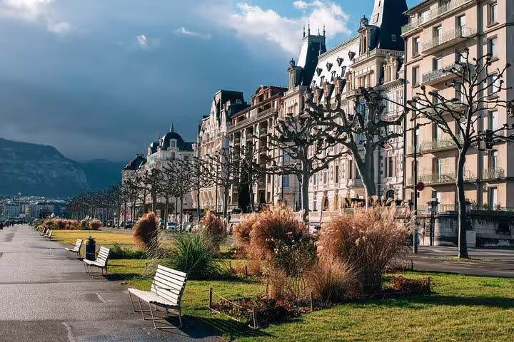 Historic Belle Époque buildings along Geneva lakefront promenade with bare trees and park benches