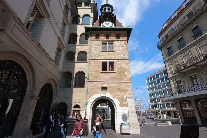Historic medieval clock tower gate in Geneva with pedestrians walking through arched passage