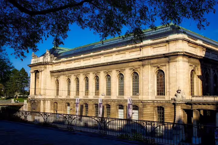 Neoclassical stone building with arched windows and green copper roof in Geneva, Switzerland