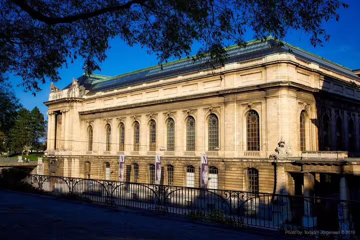 Neoclassical stone building with arched windows and green roof in Geneva, Switzerland on a sunny day