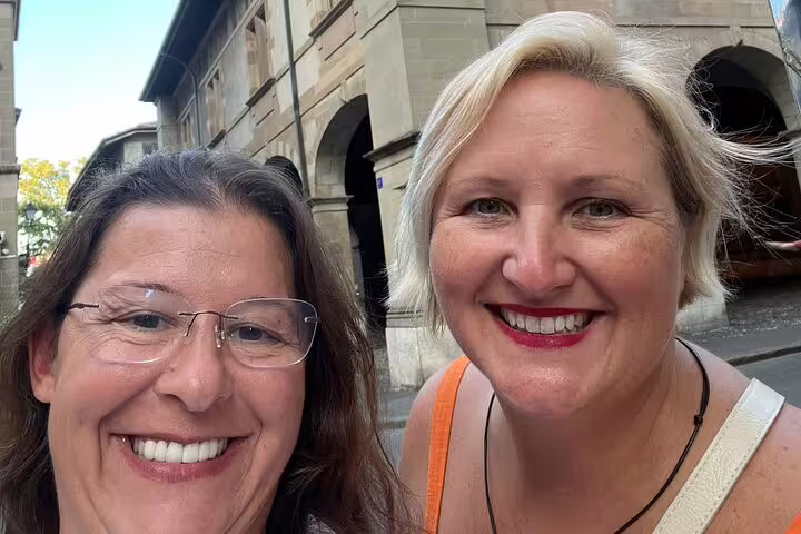 Two smiling women on a guided walking tour in Geneva city streets
