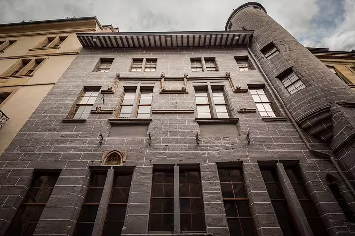 Historic stone building facade with gothic details in Geneva old town, viewed from below