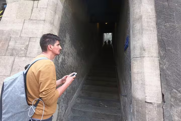 Tourist with smartphone exploring a narrow stone stairway passage in Geneva city walk