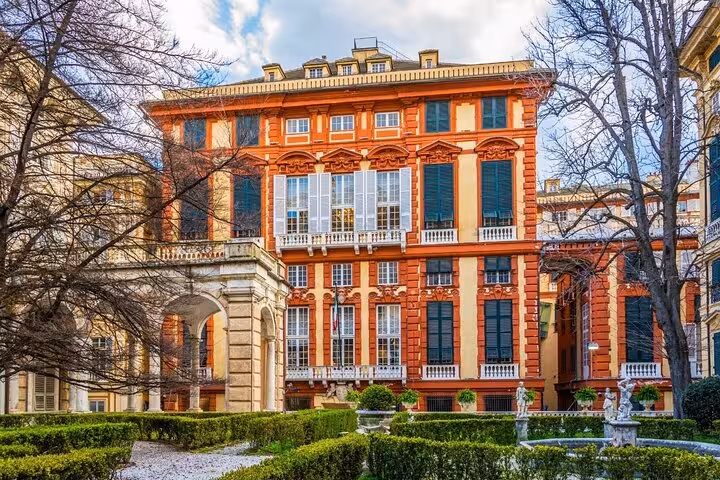 Ornate red and cream Baroque palace with manicured gardens in Genoa, Italy