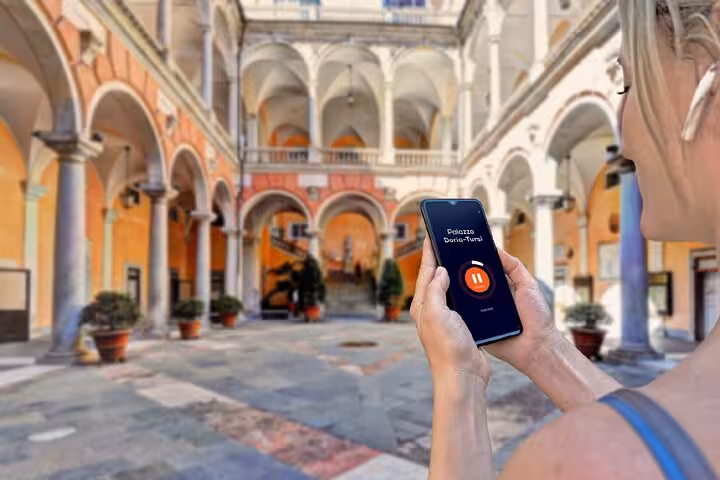 Tourist using audio guide app at Palazzo Doria-Tursi courtyard in Genoa, Italy