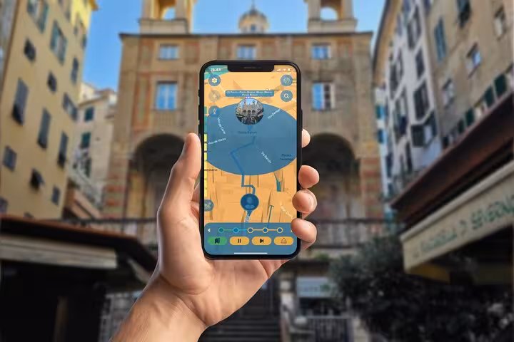 Hand holding smartphone with GPS tour app map in historic Genoa piazza with yellow buildings