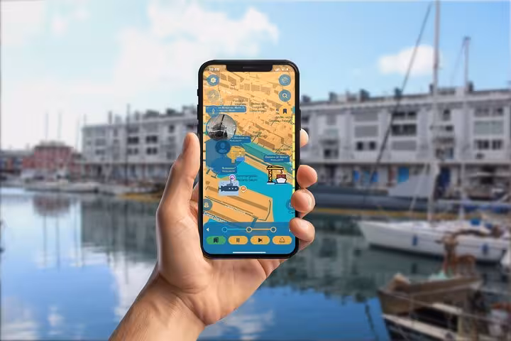 Hand holding smartphone displaying GPS self-guided tour map of Genoa's harbor and docks