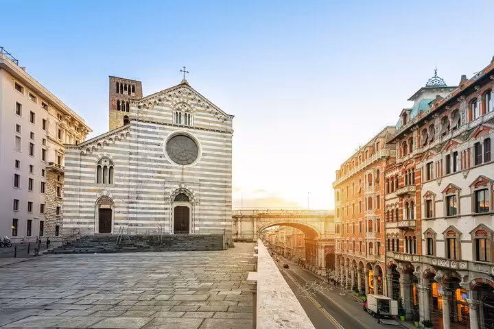 Striped marble church facade and historic boulevard in Genoa city center at sunrise