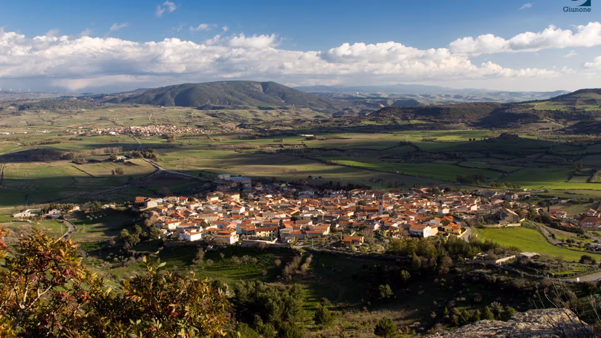 Panoramic view of Genoni village nestled in lush green valleys, offering a glimpse of Sardinia's natural beauty.