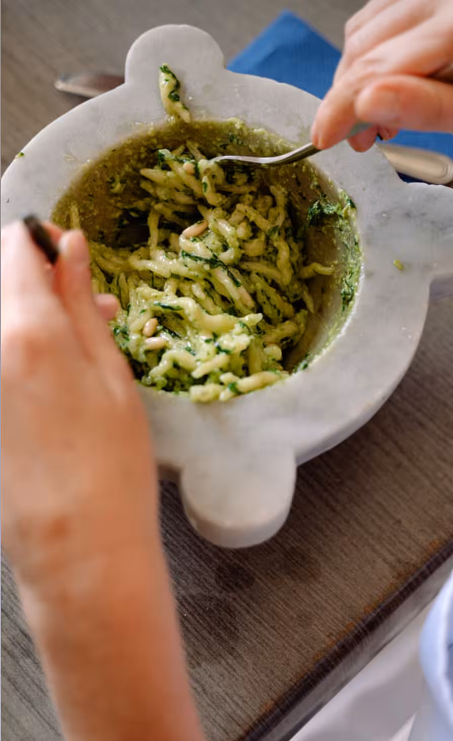 Close-up of traditional Genovese pesto being mixed in a marble mortar during a hands-on cooking class.