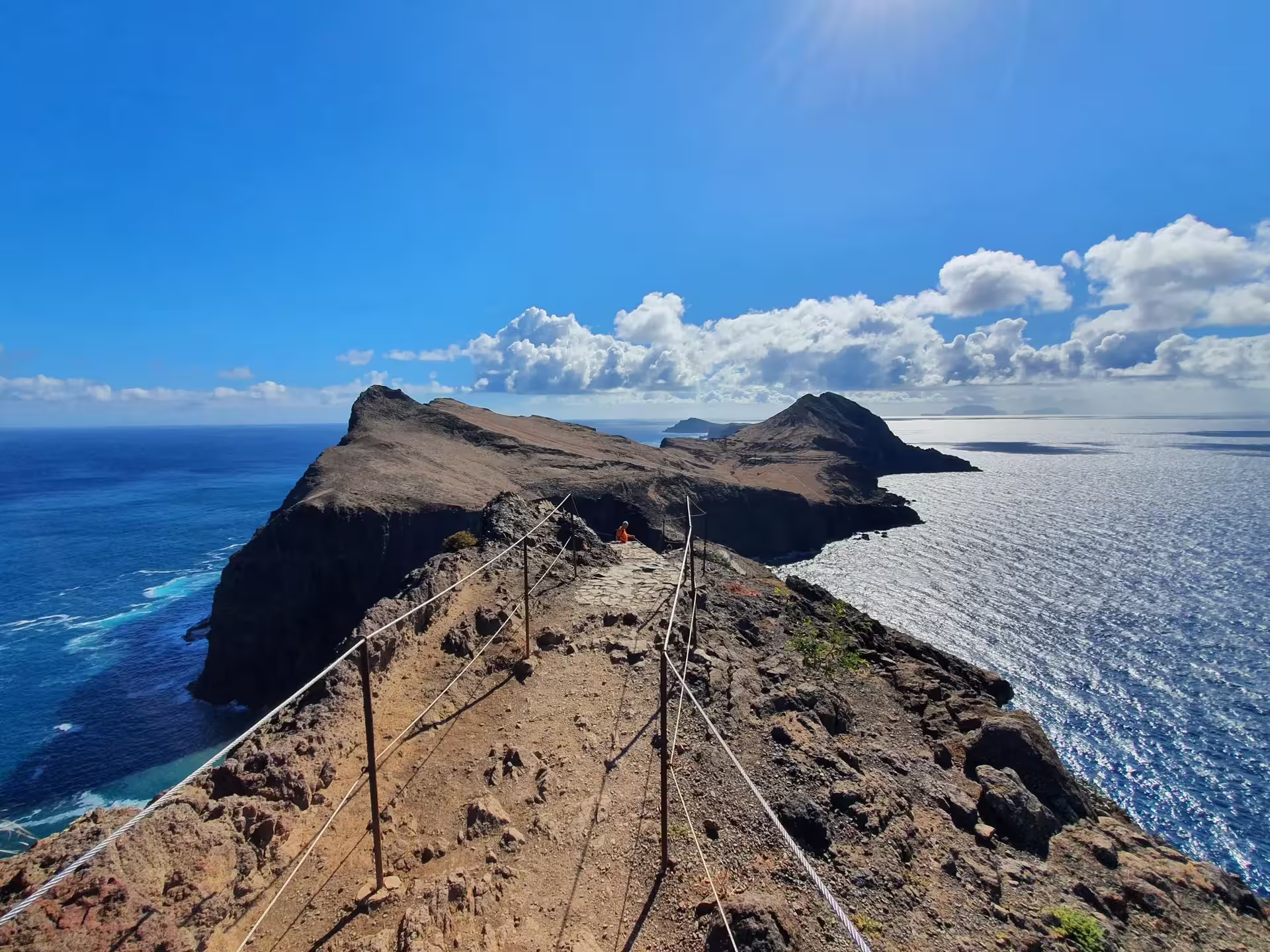 Breathtaking cliffside trail overlooking vast ocean vistas under clear blue skies on The Geological Hike adventure.