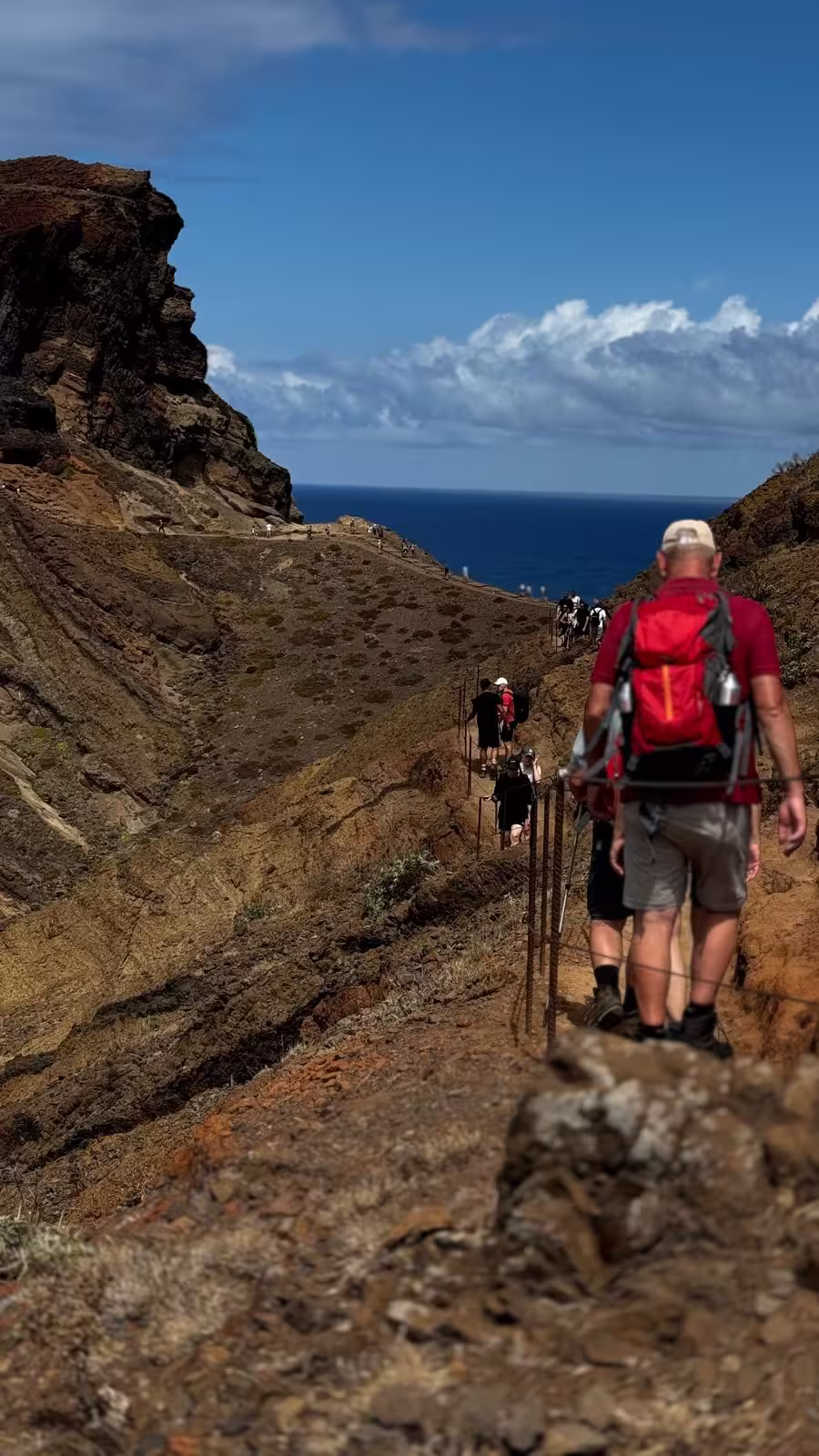 Hikers traverse a rugged coastal trail during The Geological Hike with stunning ocean views and rocky cliffs.